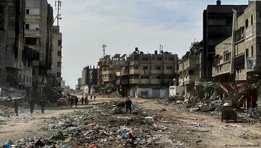 People walk near damaged houses in the Zeitoun neighbourhood of Gaza City after Israeli forces withdrew from the area